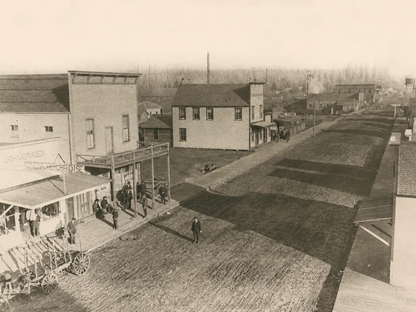 Elevated view along an unpaved downtown Marysville street with storefronts and pedestrians