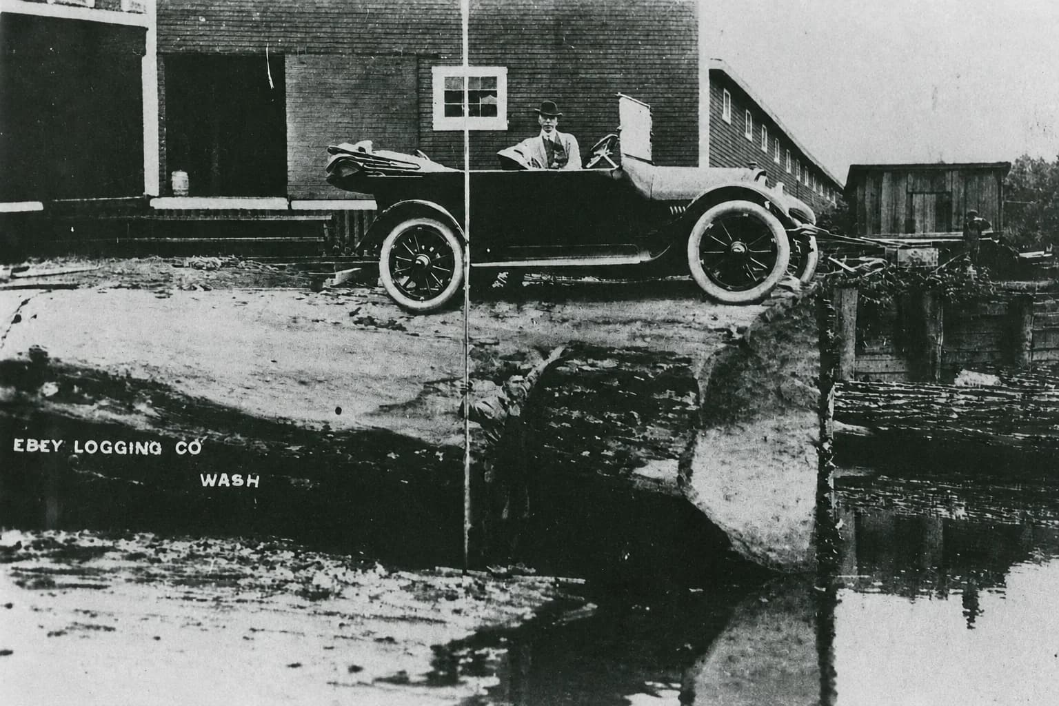 Early automobile parked above a log pond at the Ebey Logging Company