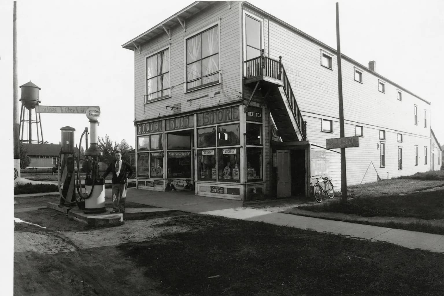 Golden Rule Store in Marysville with a shopkeeper, early gas pumps, and a bicycle