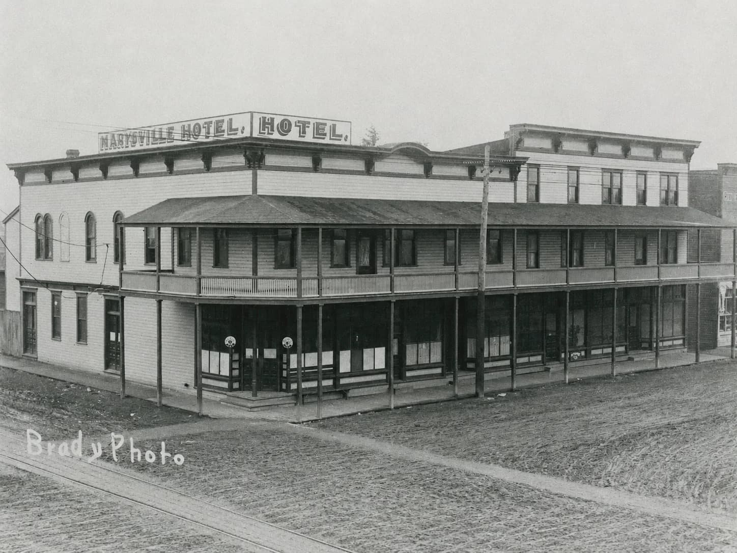 Two-story Marysville Hotel with a wraparound balcony on an unpaved street