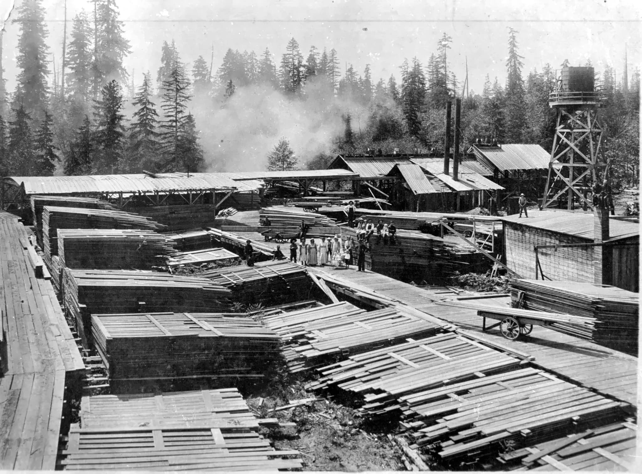 Marysville sawmill with workers, stacked lumber, mill buildings, smokestacks, and a water tower
