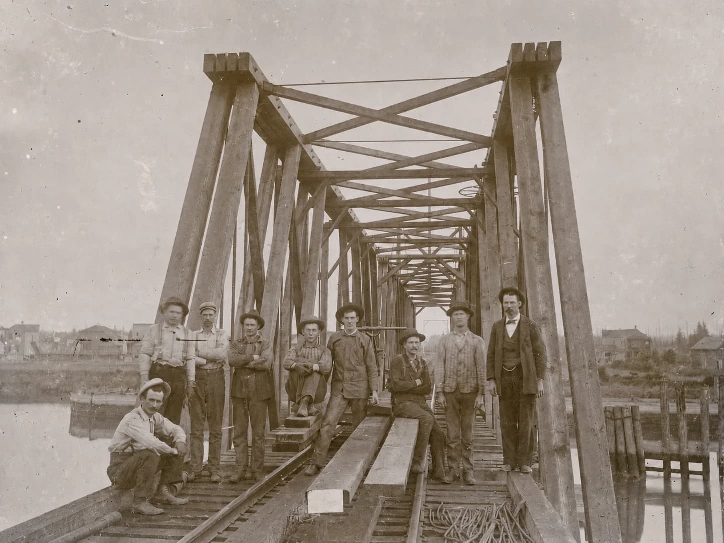 Construction crew posed on the tracks of a timber railroad bridge