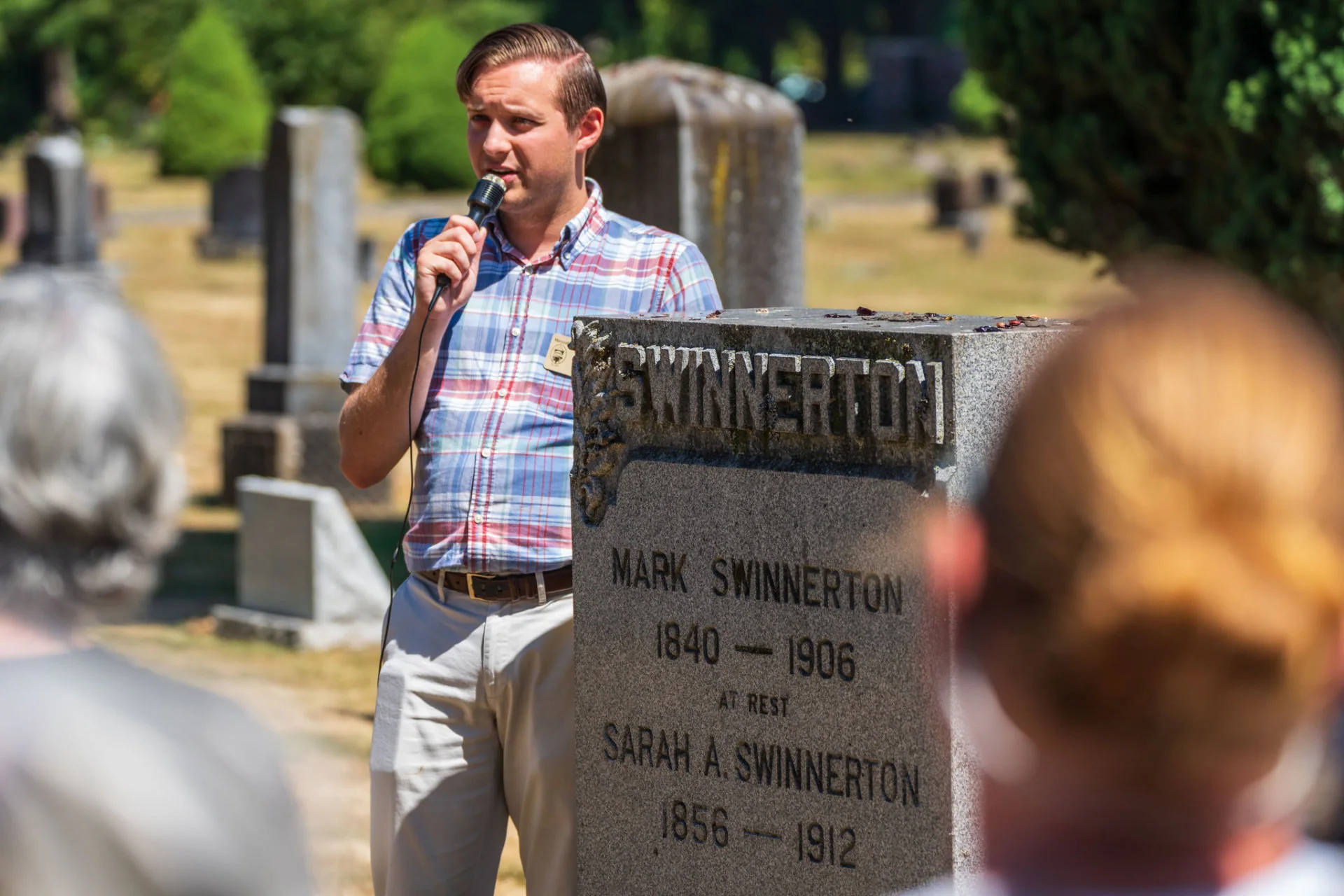 A guide shares the history of the Swinnerton family beside their gravestone